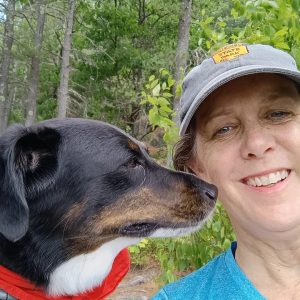 multi-colored dog giving her mom a kiss on a trail